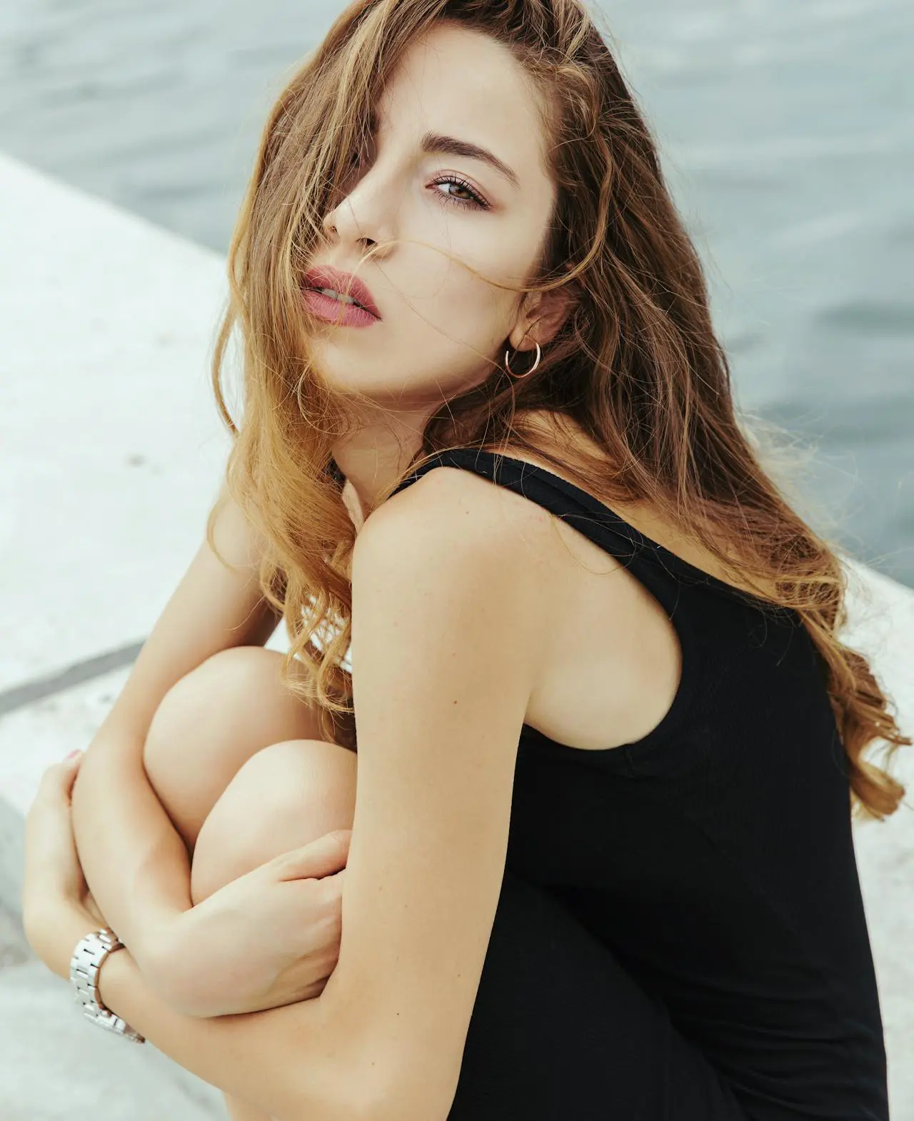 A confident woman with long brown hair sits, reflecting Refresh MedSpa's cosmetic results.