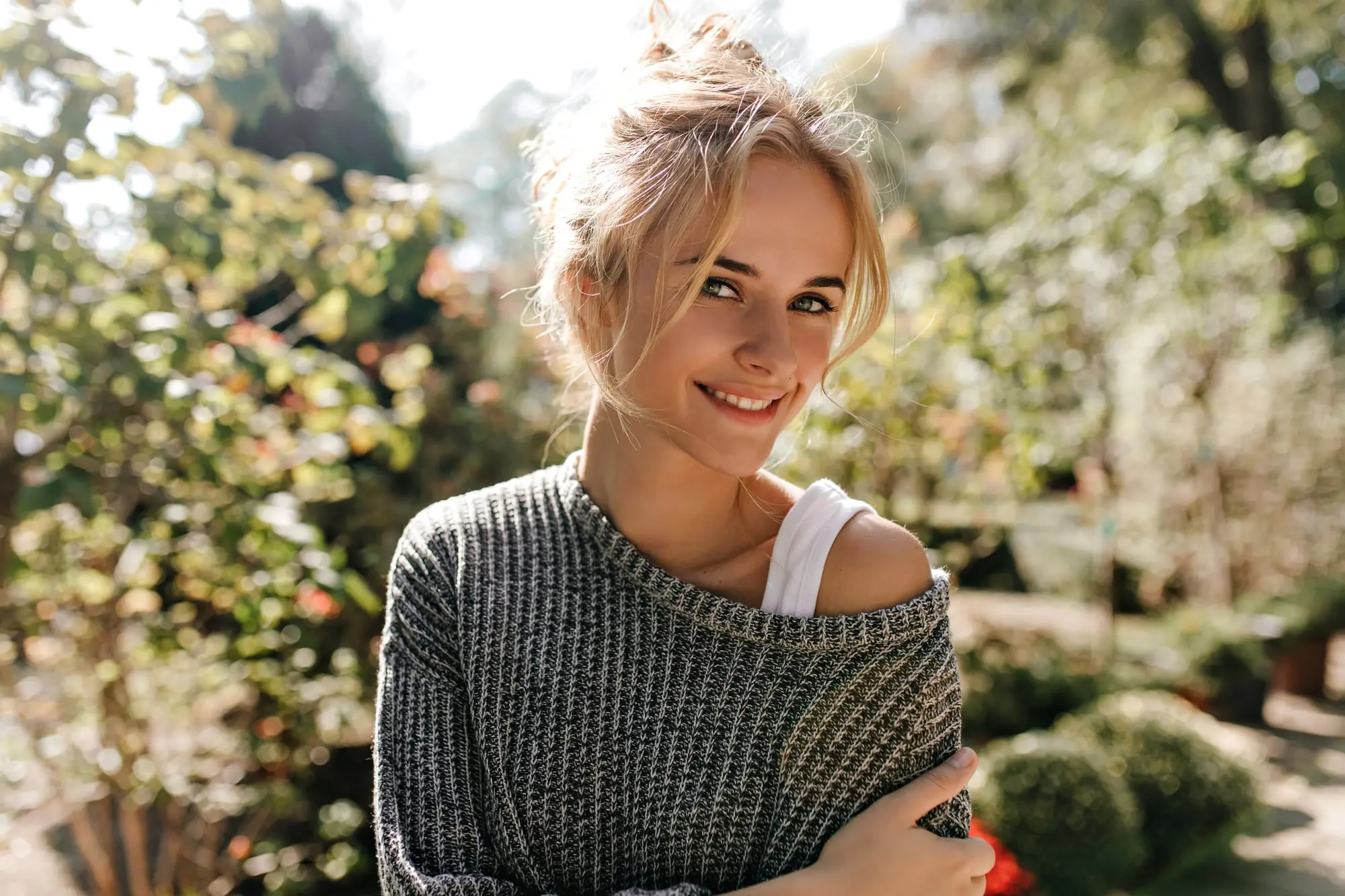 Smiling young woman in a garden, radiant skin glowing—at Refresh MedSpa after BBL Photofacial treatments.