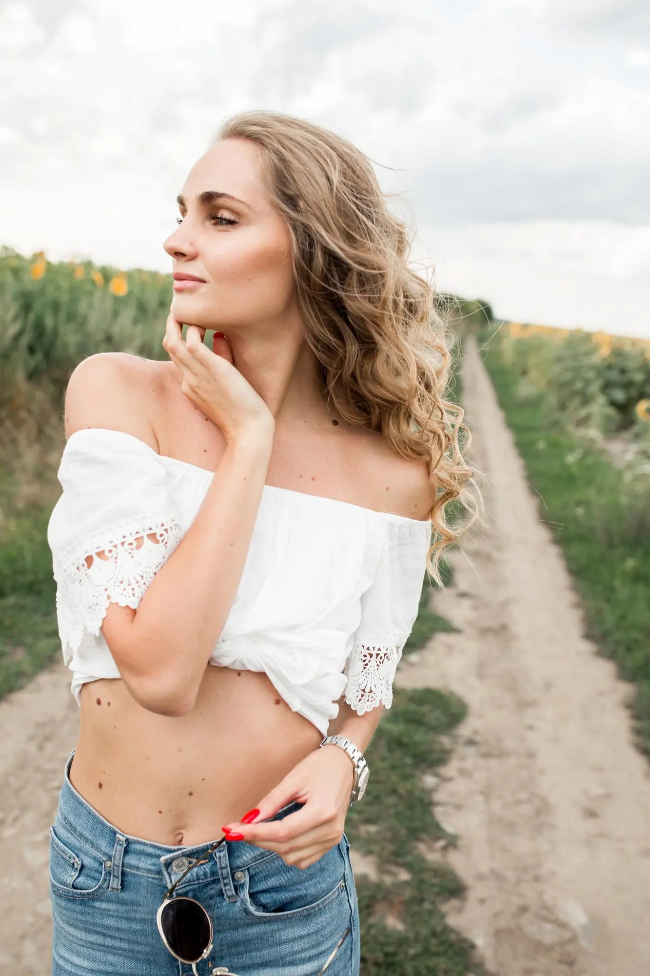 On a rural path in Cape Coral, FL, a woman with jawline slimming from Refresh MedSpa holds sunglasses, looking to the side.
