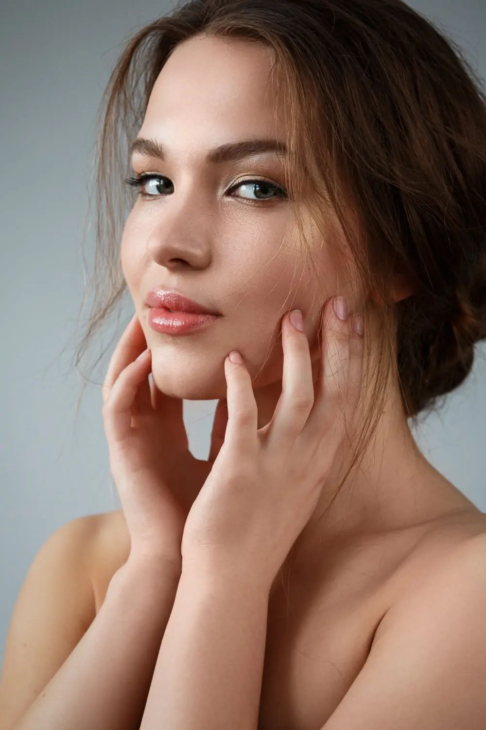 At Refresh MedSpa in Cape Coral, FL, a woman with light makeup and brown hair touches her face, subtly showing melasma.