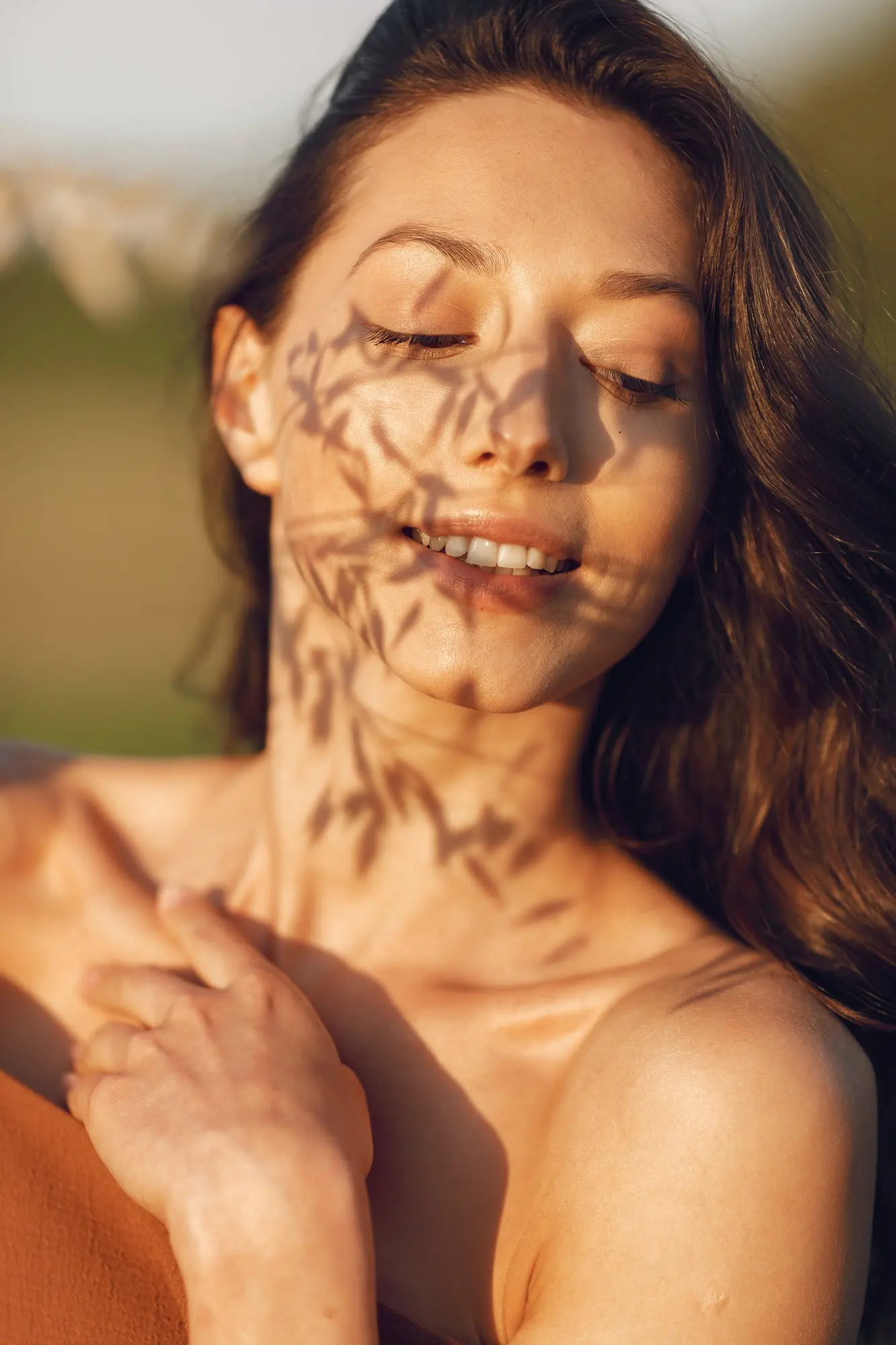 Outside Refresh MedSpa in Cape Coral, FL, a woman with long brown hair and melasma stands in sunlight, hand on her shoulder.