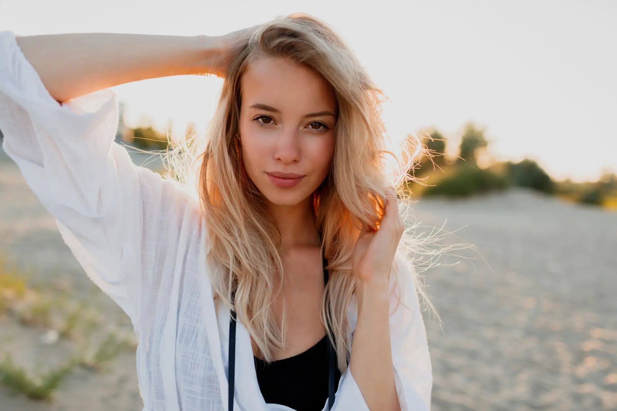 On a sandy beach at sunset in Cape Coral, FL, a long-haired person with subtly sagging skin faces the camera for Refresh MedSpa.