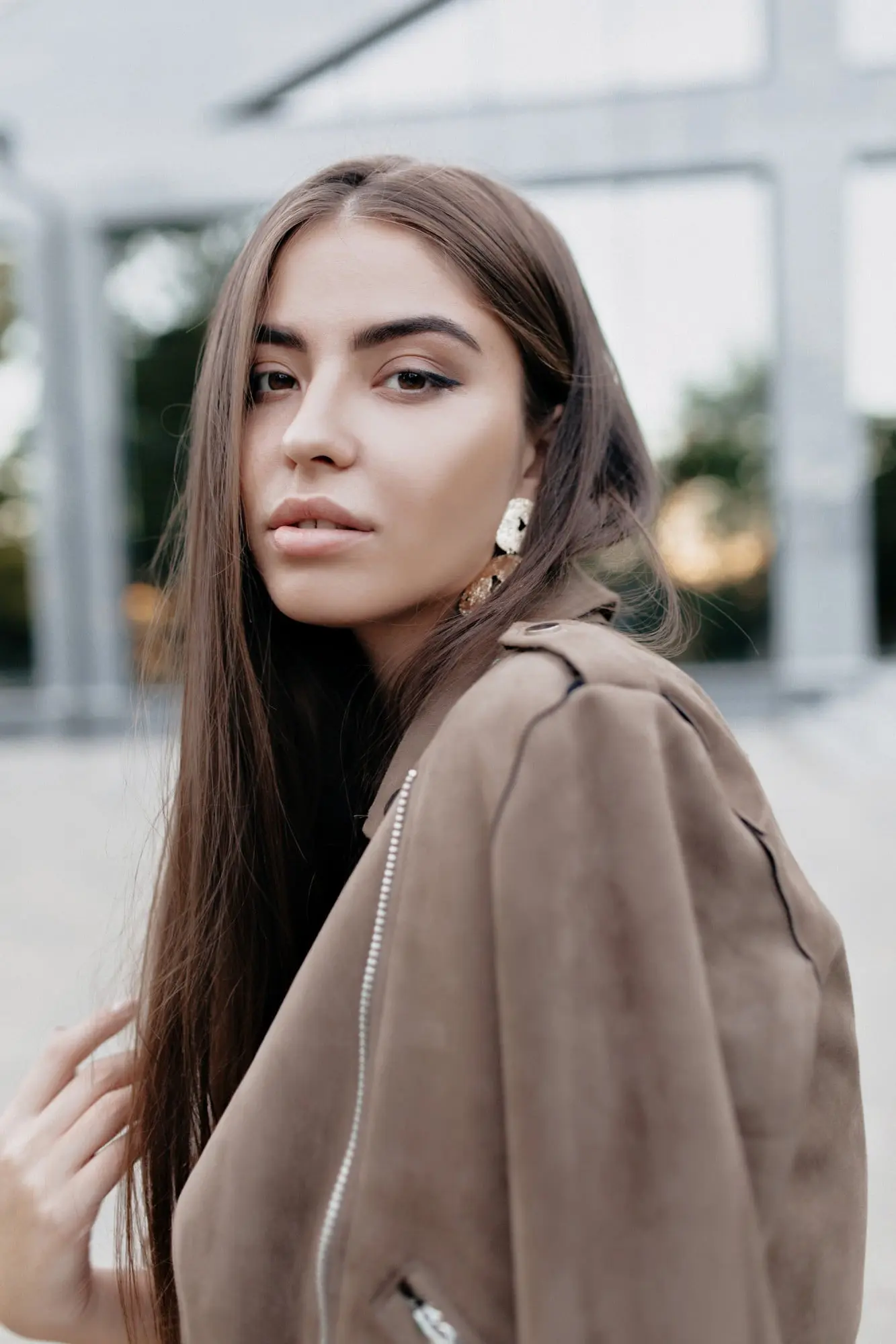 Posing outdoors, a young woman with long brown hair stands by a modern building at Refresh MedSpa in Cape Coral, FL.