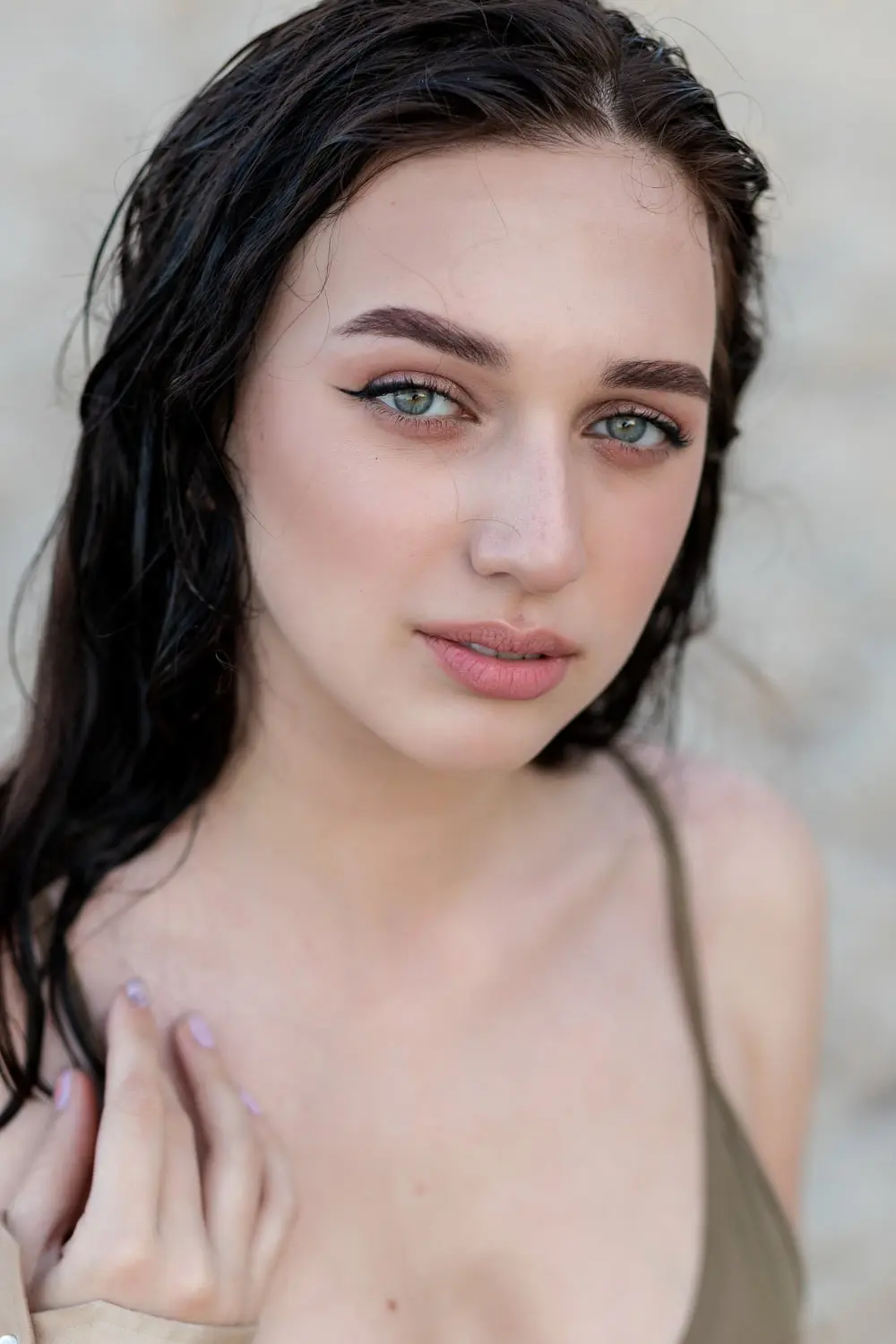 A woman with wet dark hair and blue eyes, showing volume loss, gazes at the camera near Refresh MedSpa in Cape Coral, FL.