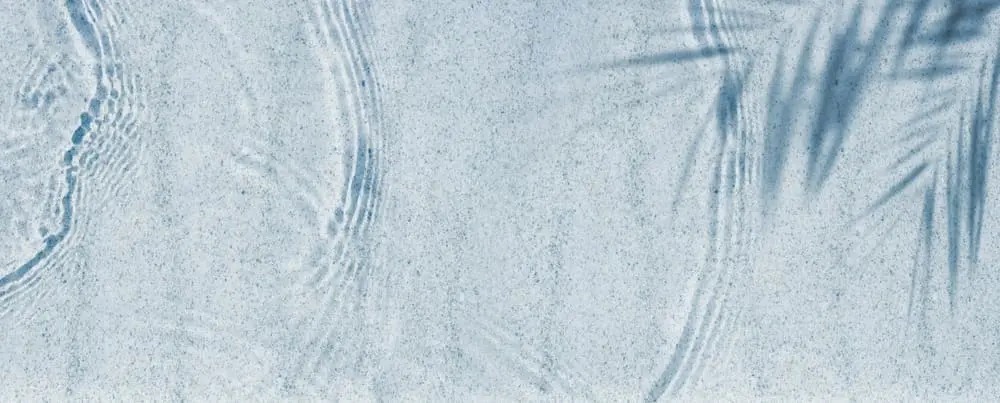 Shallow water with gentle ripples and the shadow of palm leaves cast on a light blue surface, reminiscent of relaxing days in Cape Coral, where botox Cape Coral FL treatments offer rejuvenation and coastal tranquility.