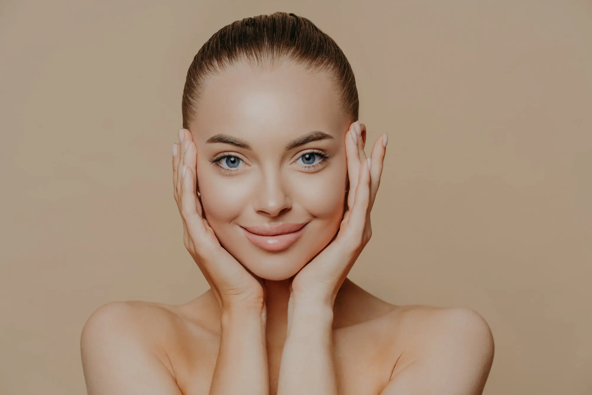 A smiling young woman with clear skin holds her face, showing Botox confidence at Refresh MedSpa.