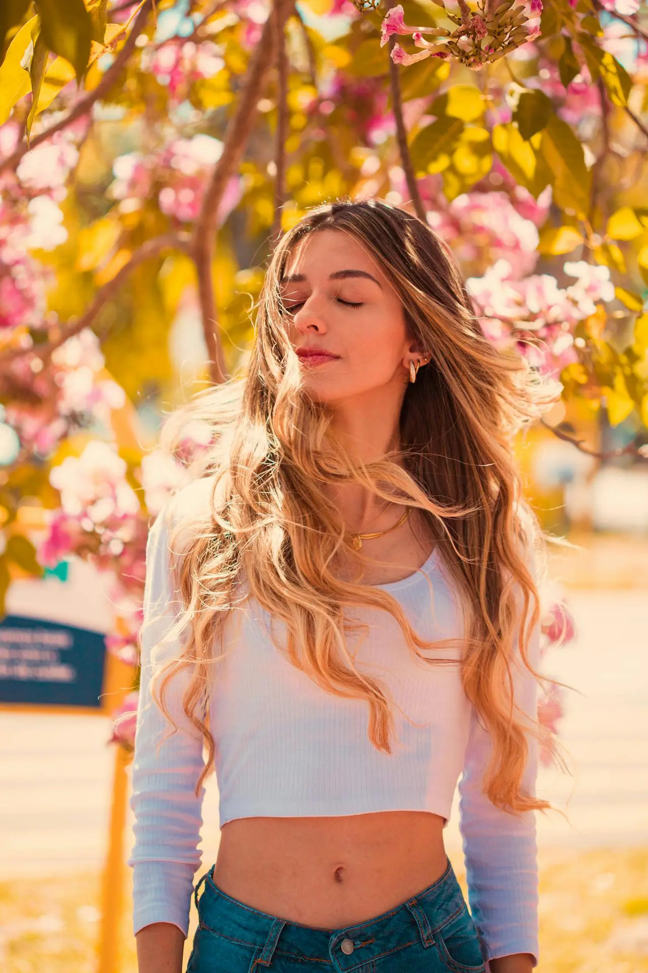 A young woman with blonde wavy hair enjoys spring blooms, showing off a refreshed look from Refresh MedSpa.