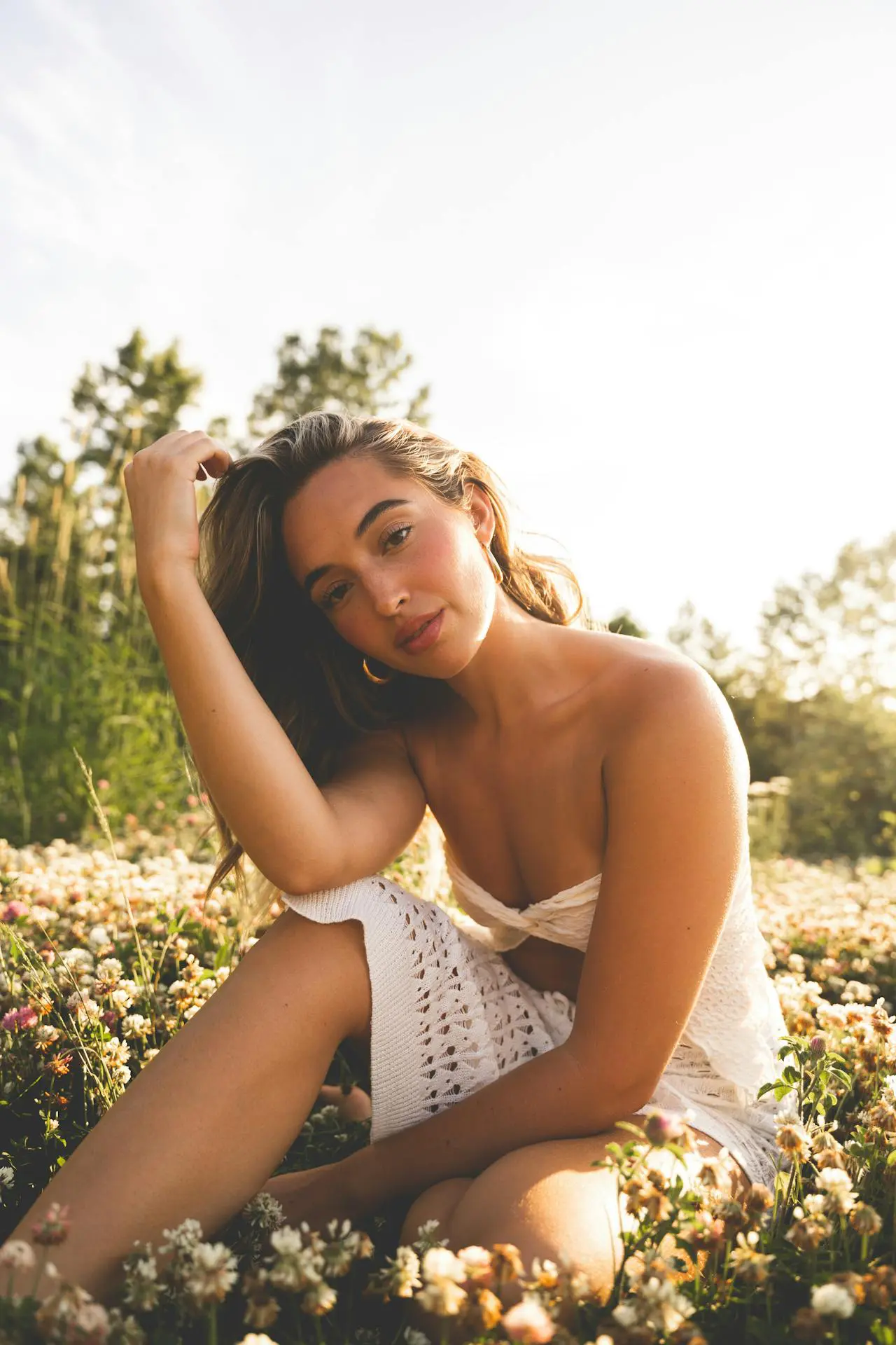 In a flower field, a woman in white with glowing skin, reflecting non-surgical facial rejuvenation at Refresh MedSpa.