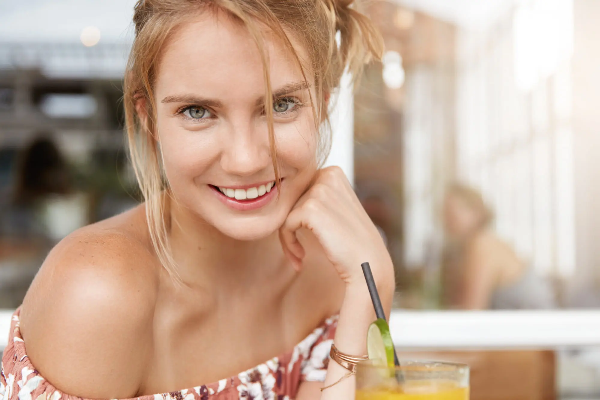 At Refresh MedSpa, a glowing woman with light hair and blue eyes smiles beside a yellow lime-garnished drink.