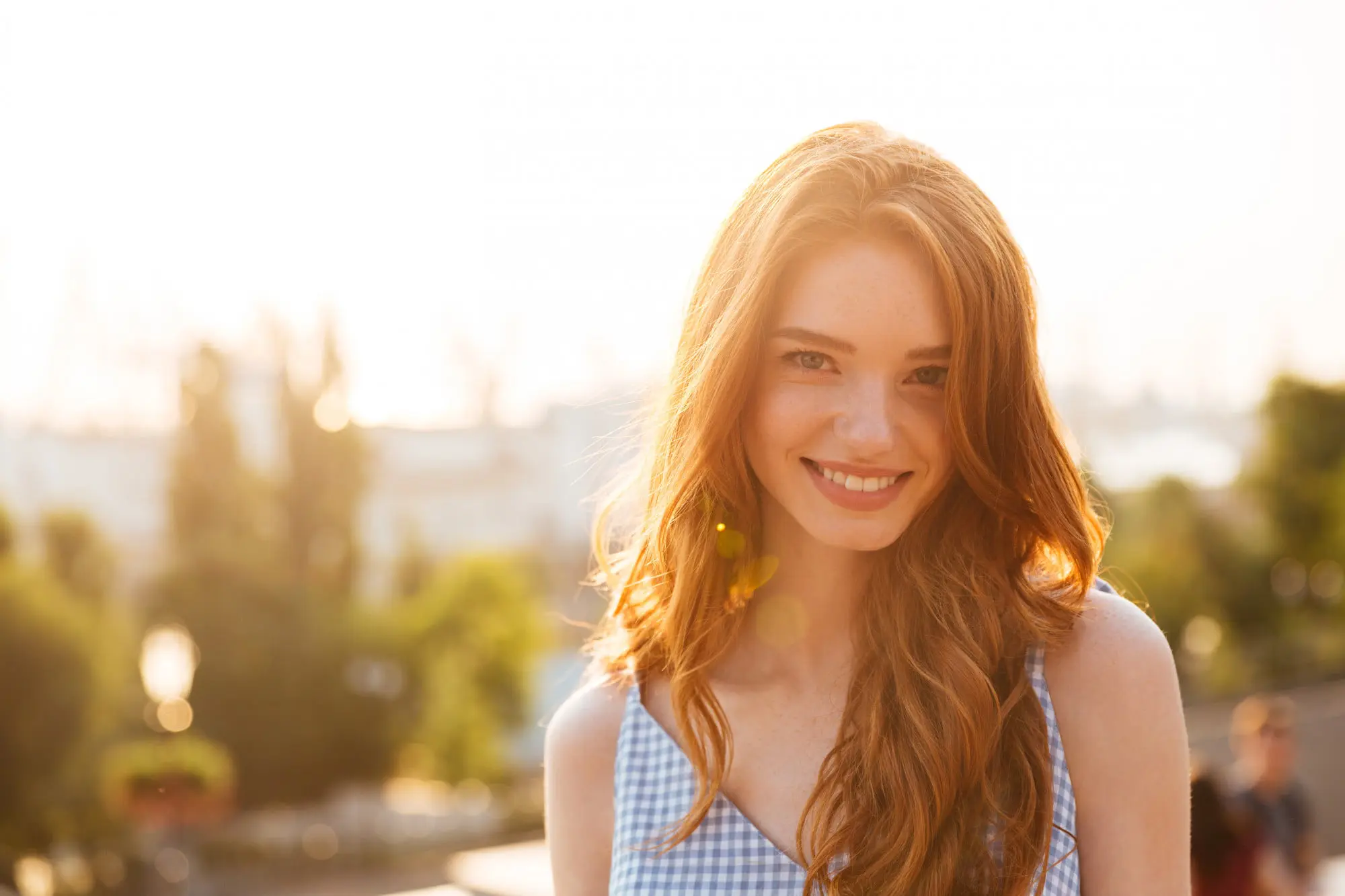 Smiling outdoors, a young woman with glowing skin from Forever Clear BBL at Refresh MedSpa.