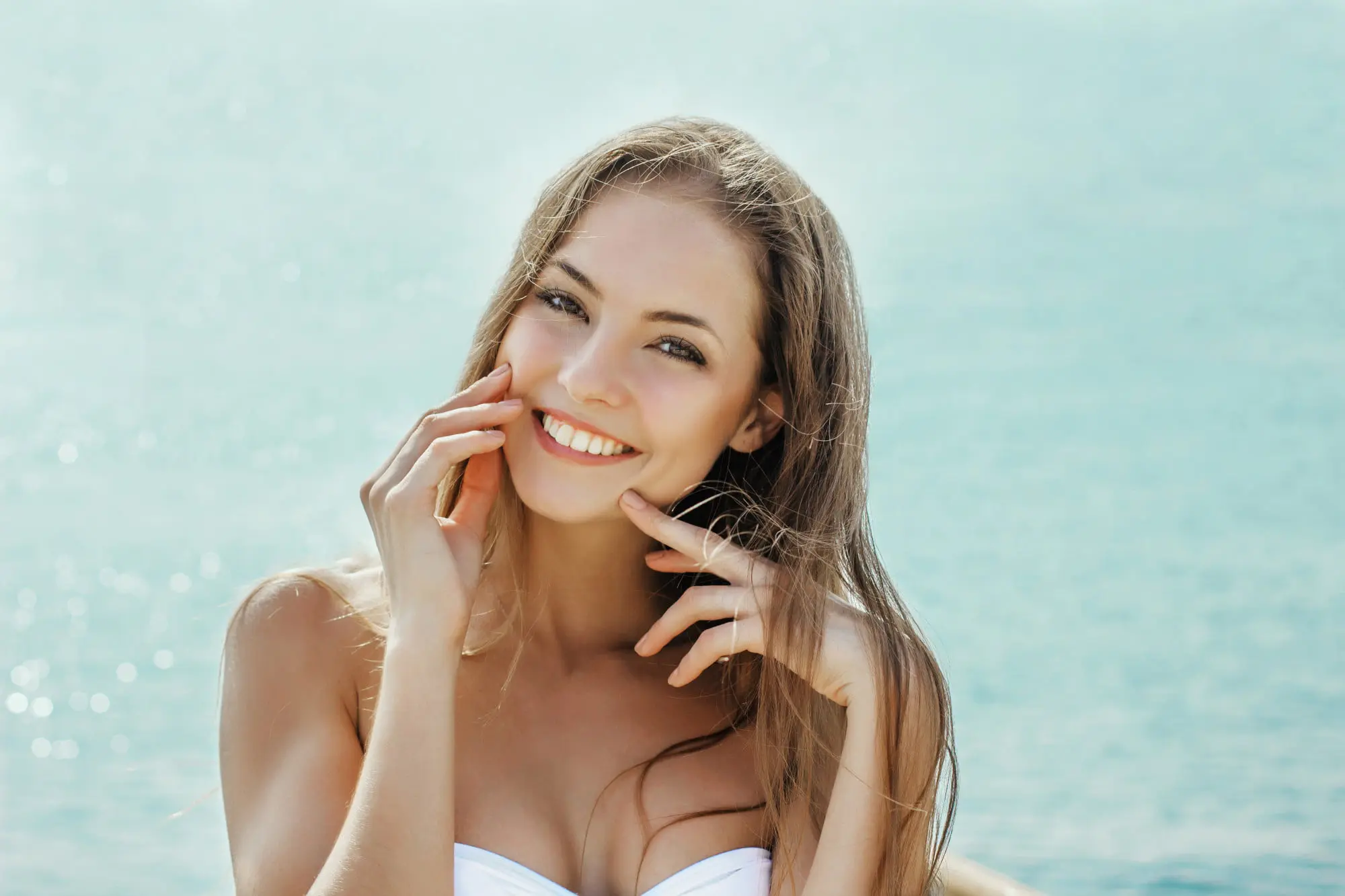 A young woman with forever clear BBL-treated skin smiles by the water, showcasing Refresh MedSpa’s results.