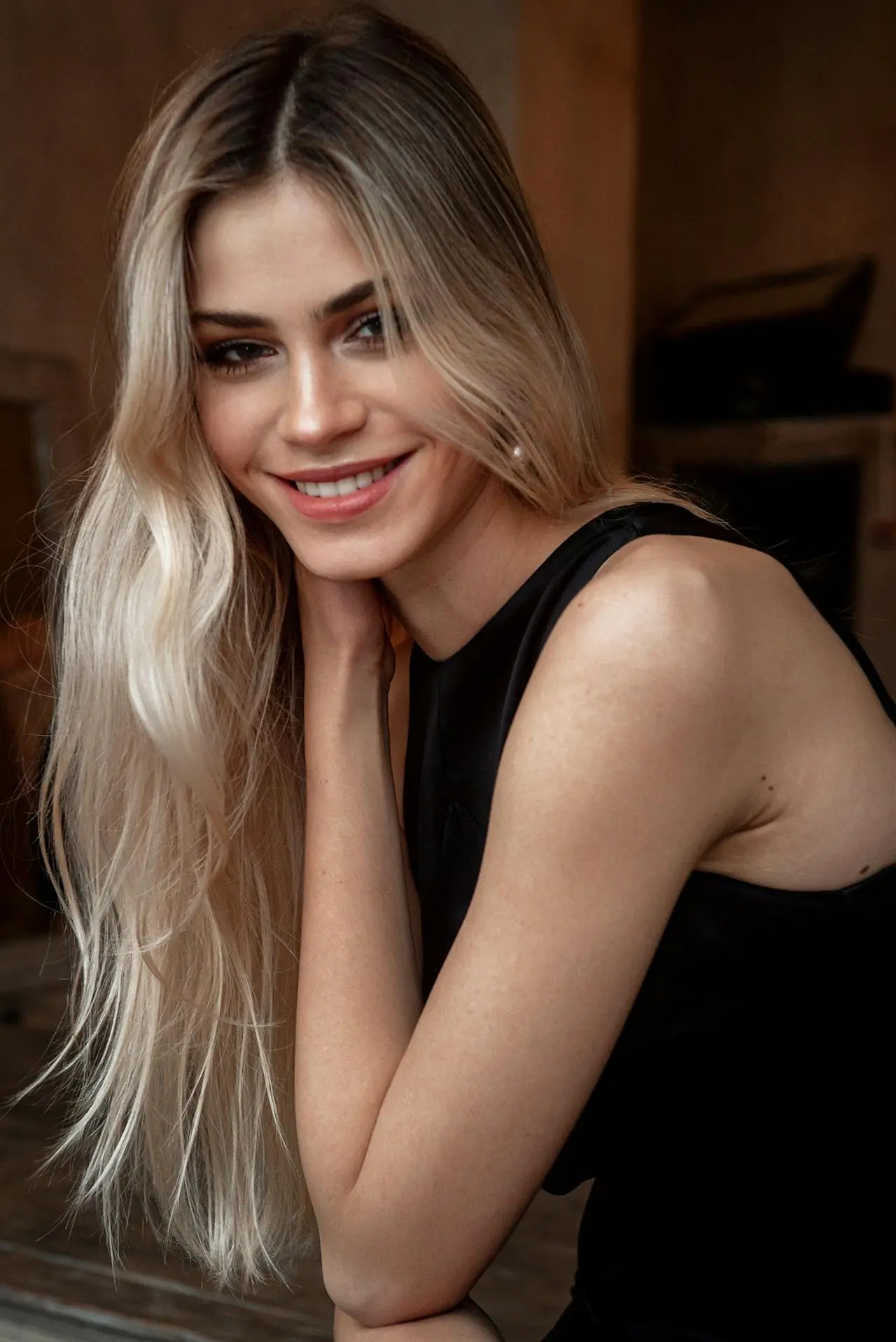 At Refresh MedSpa, a smiling blonde woman in a black top rests her hand on her neck, showing Restylane results.