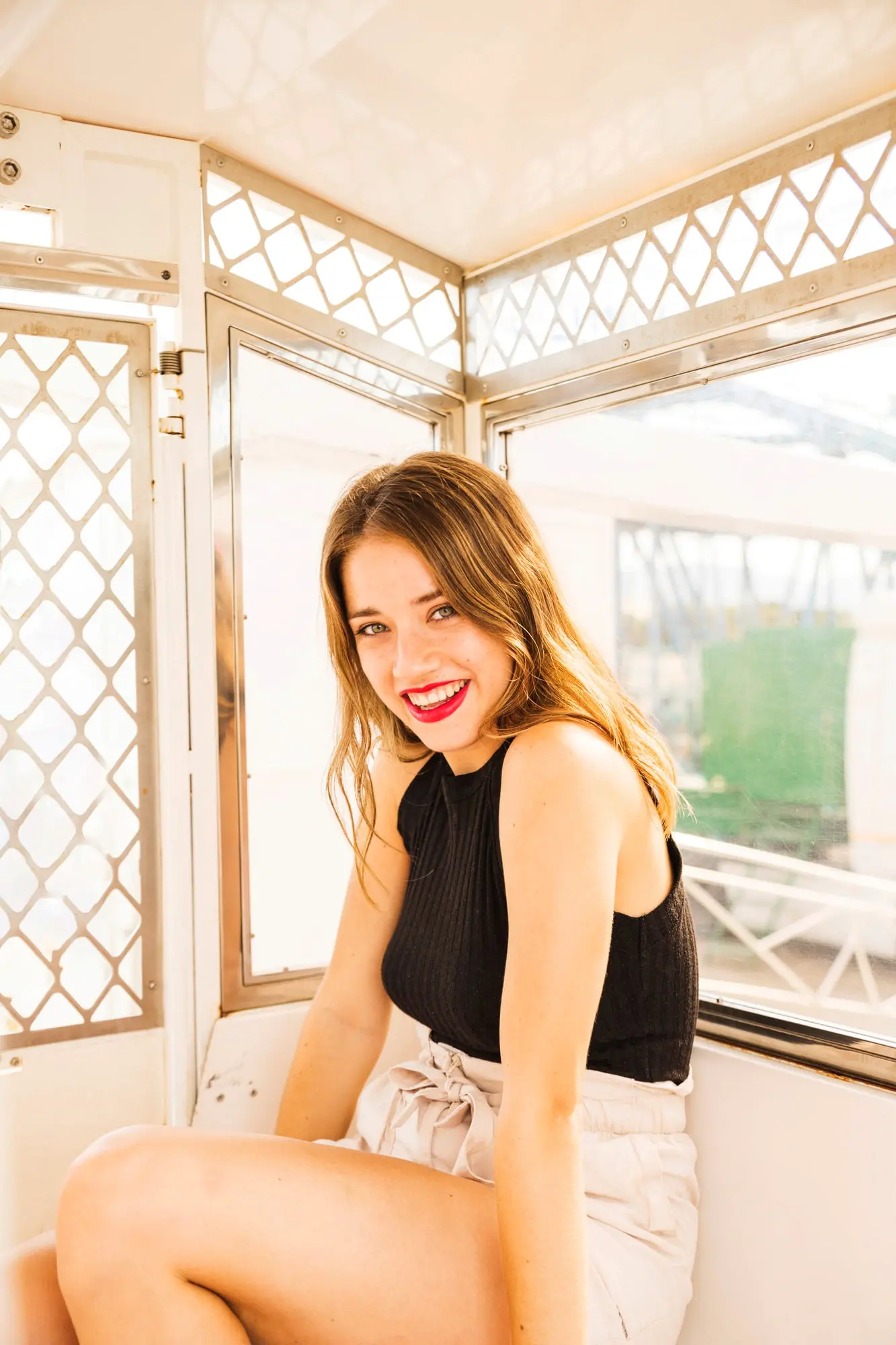 Smiling, a young woman with long brown hair sits inside a bright space after getting Botox at Refresh MedSpa in Cape Coral, FL serving clients from Fort Myers.