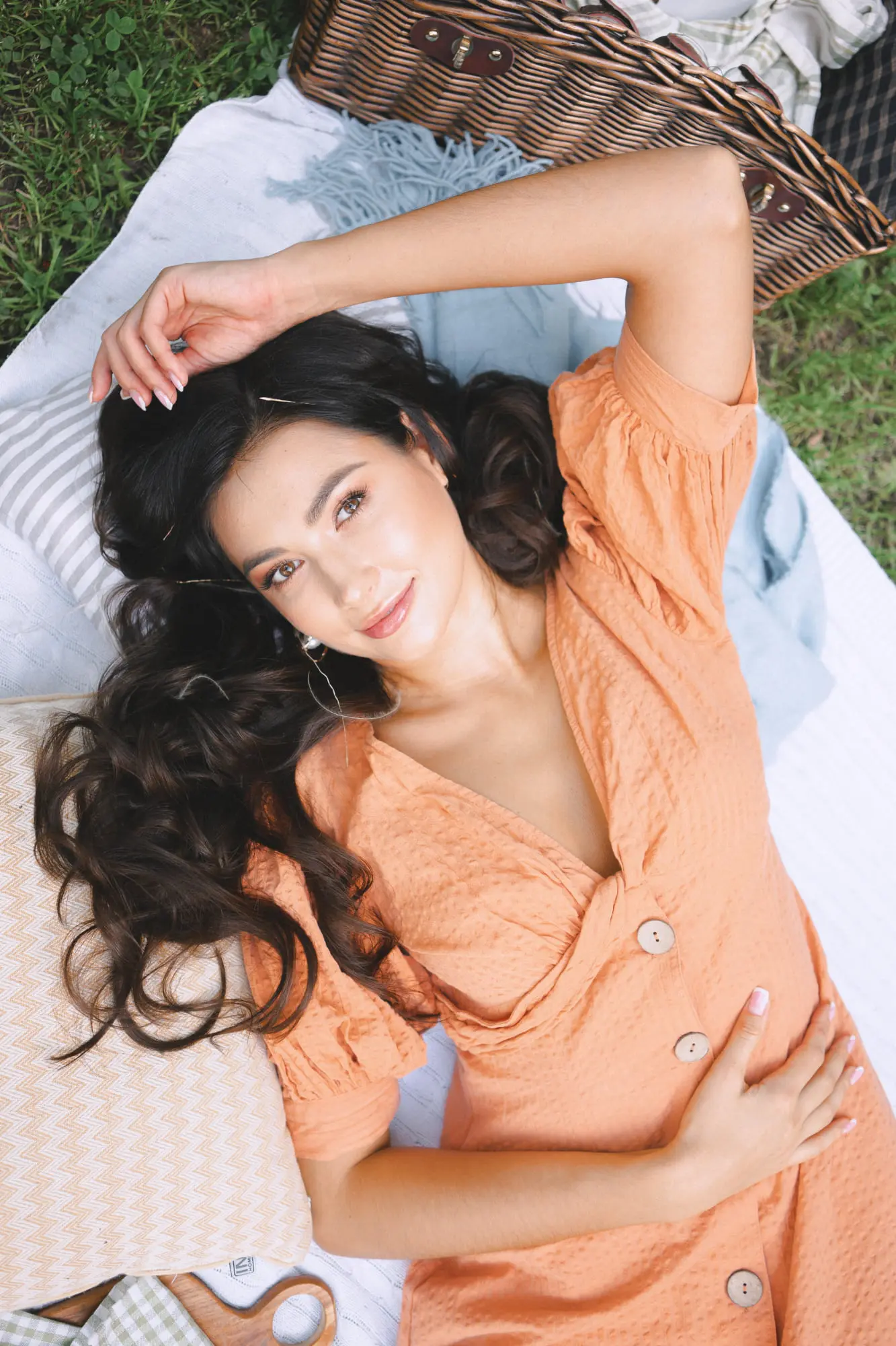 A woman in an orange dress relaxes on a blanket outdoors, glowing after a HydraFacial at Refresh MedSpa in Cape Coral, FL serving clients from Fort Myers.