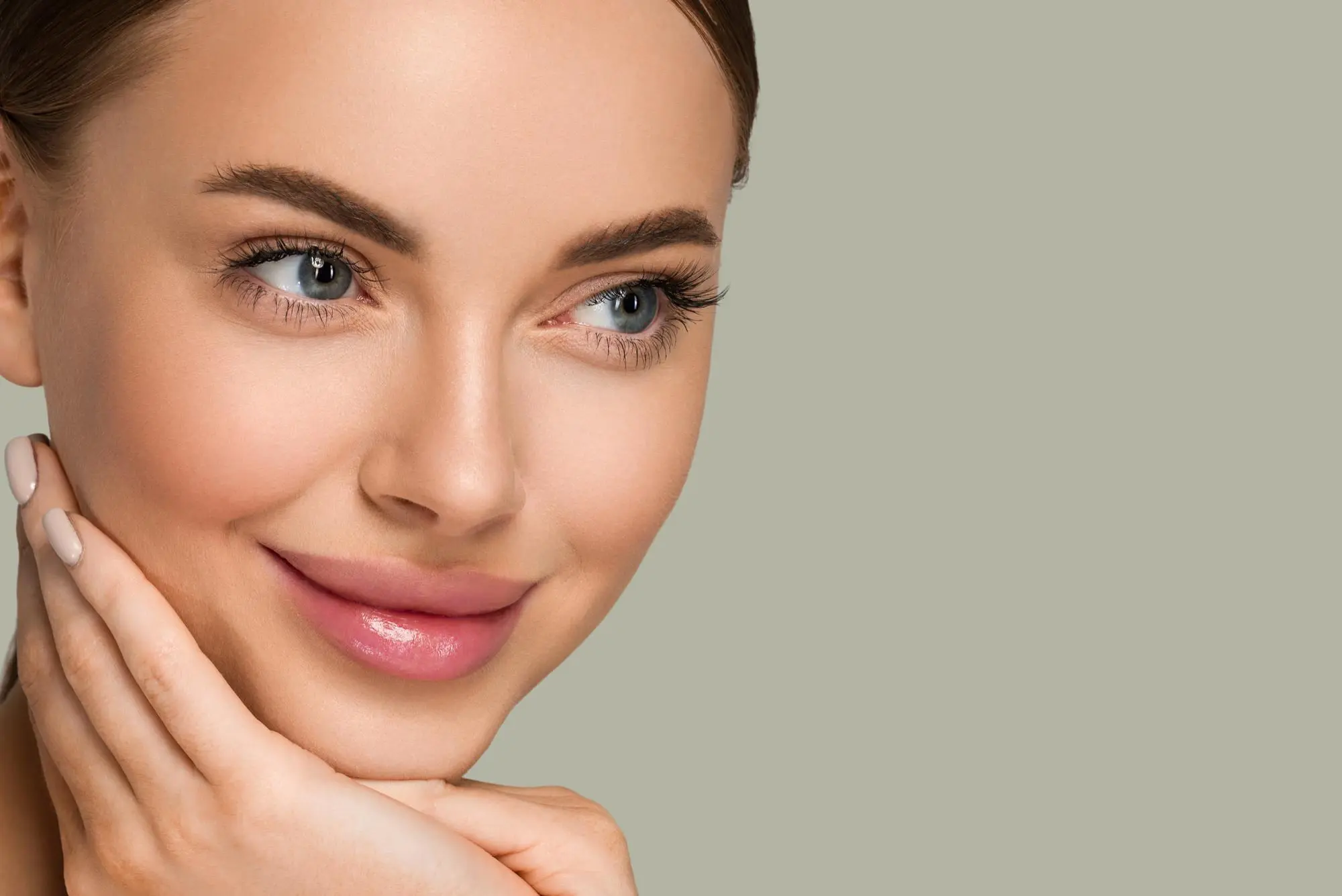 A woman with clear skin and blue eyes smiles softly, highlighting laser rejuvenation results at Refresh MedSpa.