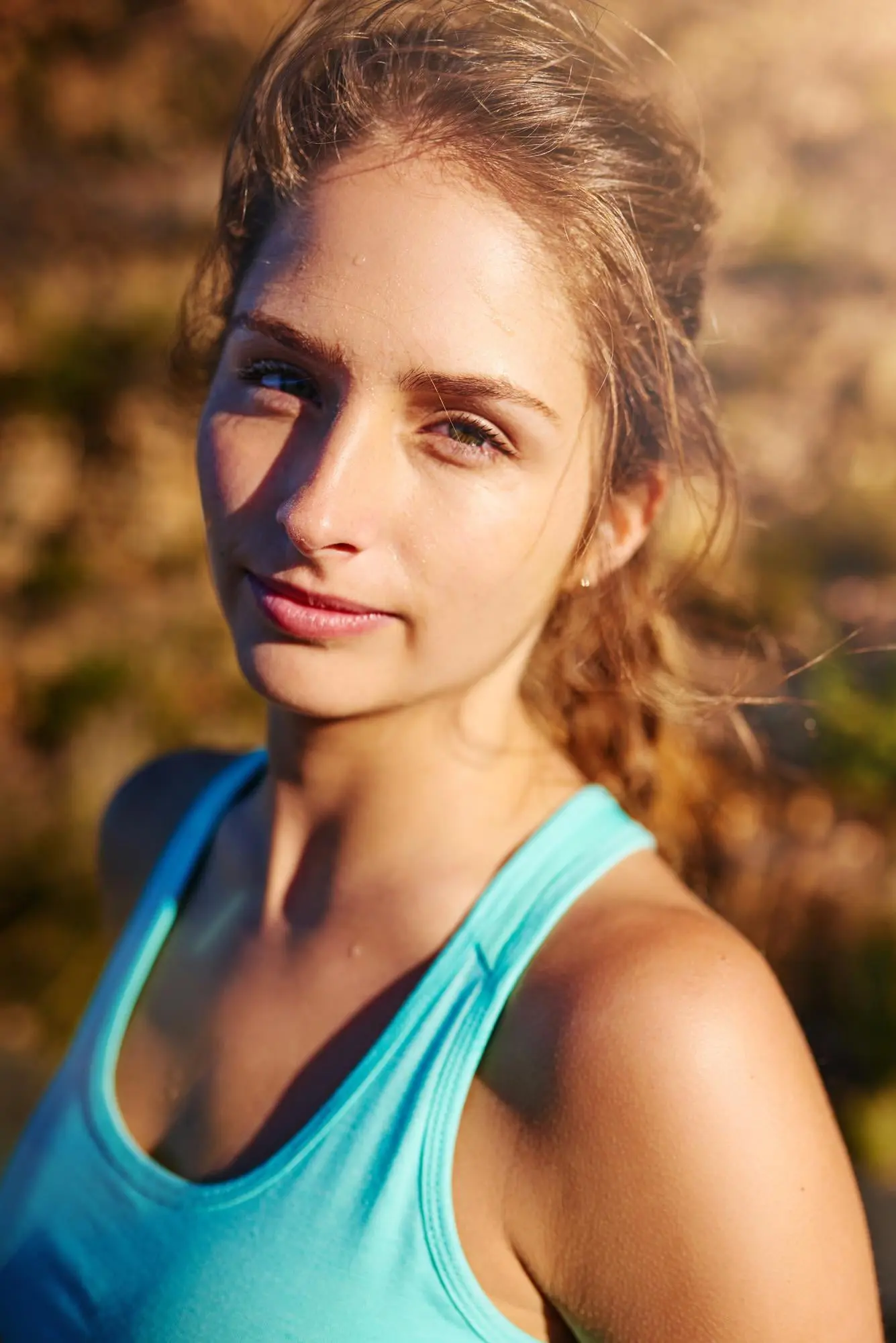 Outdoors in Cape Coral, FL, a confident young woman models the fresh look from Dysport at Refresh MedSpa, blue tank top glowing.