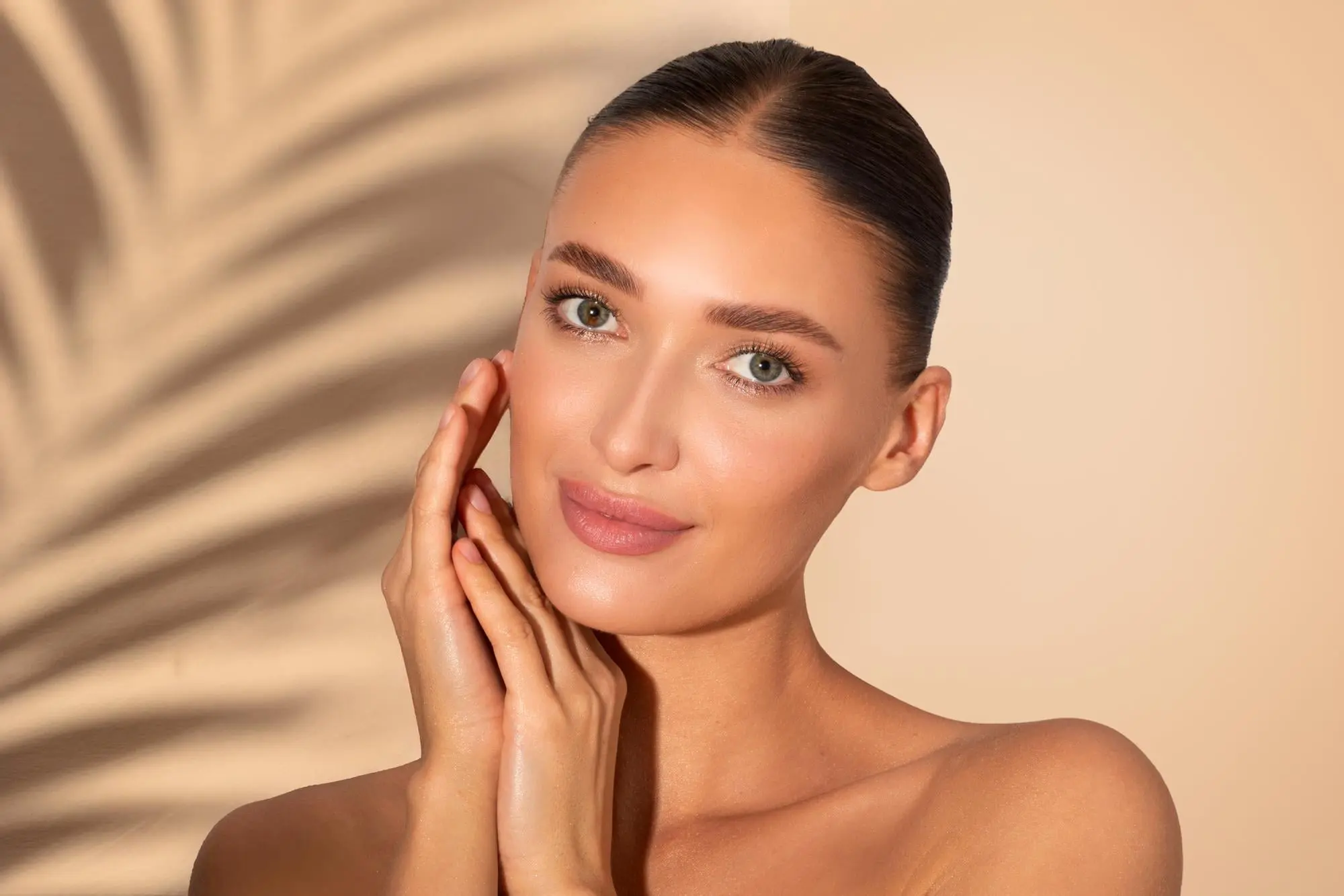 A confident woman touches her face, posing under a palm leaf shadow at Refresh MedSpa in Cape Coral, FL after laser hair removal.