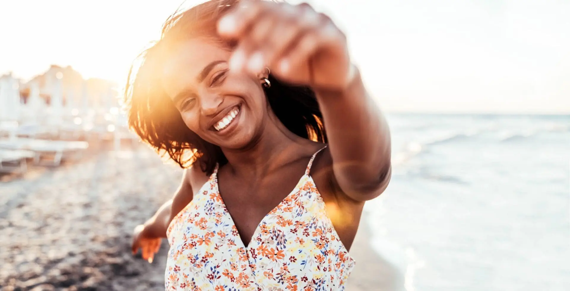On a sunny Cape Coral, FL beach, a smiling woman with radiant skin—perhaps from Refresh MedSpa—reaches toward the camera.
