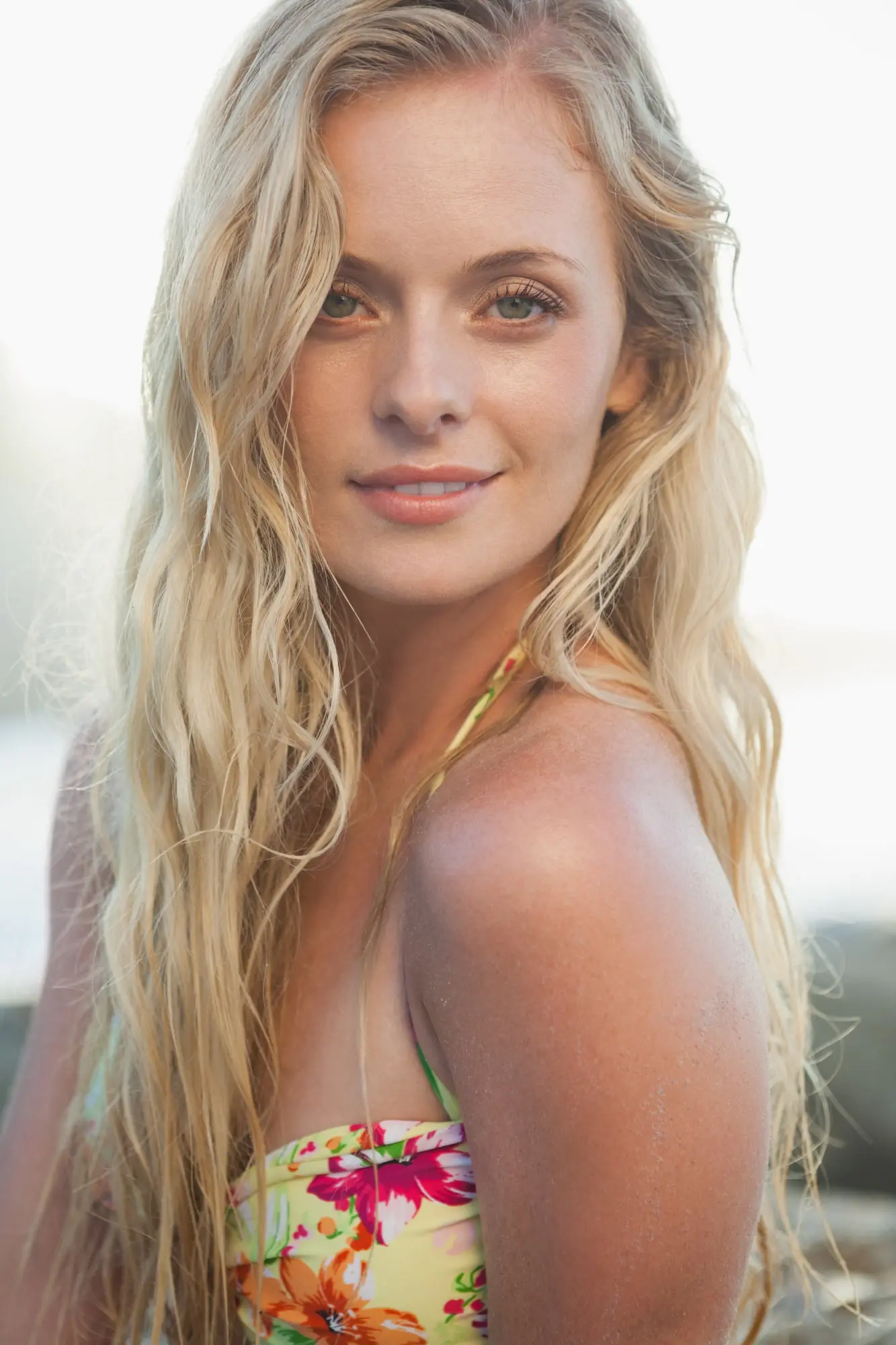 Outdoors in Cape Coral, FL, a woman with long blonde hair in a floral swimsuit looks at the camera, reflecting Refresh MedSpa’s relaxed vibe.