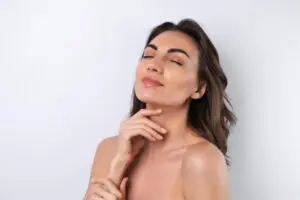 A woman with closed eyes and a slight smile touches her chin, representing Refresh MedSpa in Cape Coral, FL for Restylane results.