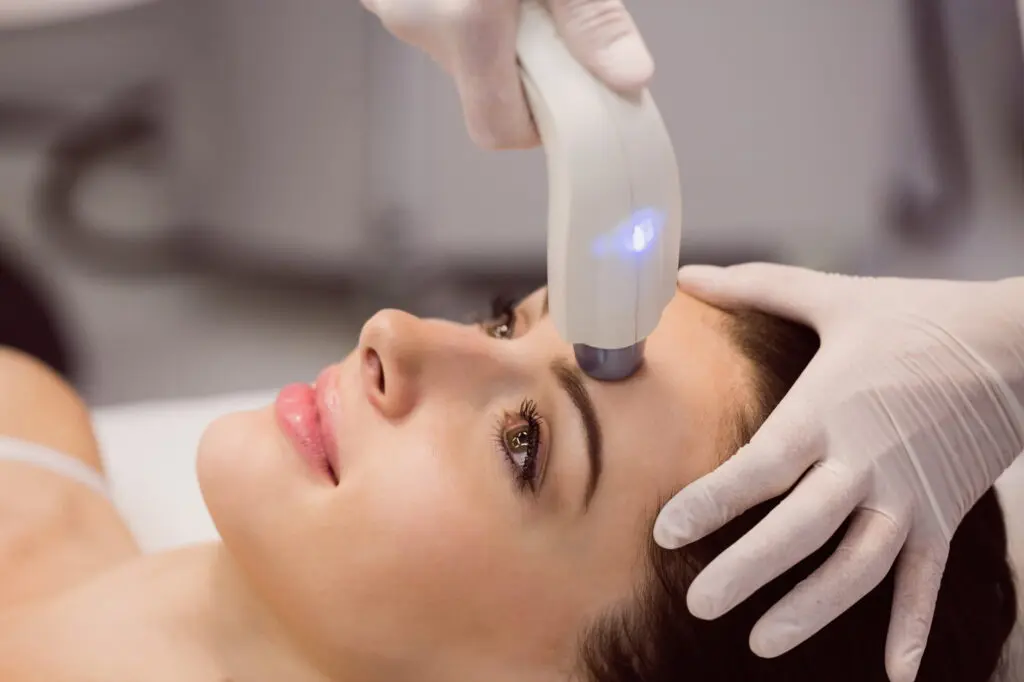 During a BBL Photofacial at Refresh MedSpa in Cape Coral, FL, a person lies down as gloved hands use a handheld device on their forehead to address skin concerns like sun damage and uneven tone.