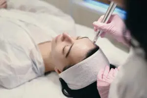 A professional in pink gloves performs microneedling with a handheld device on a person at Refresh MedSpa in Cape Coral, FL, promoting healthier, more radiant skin.