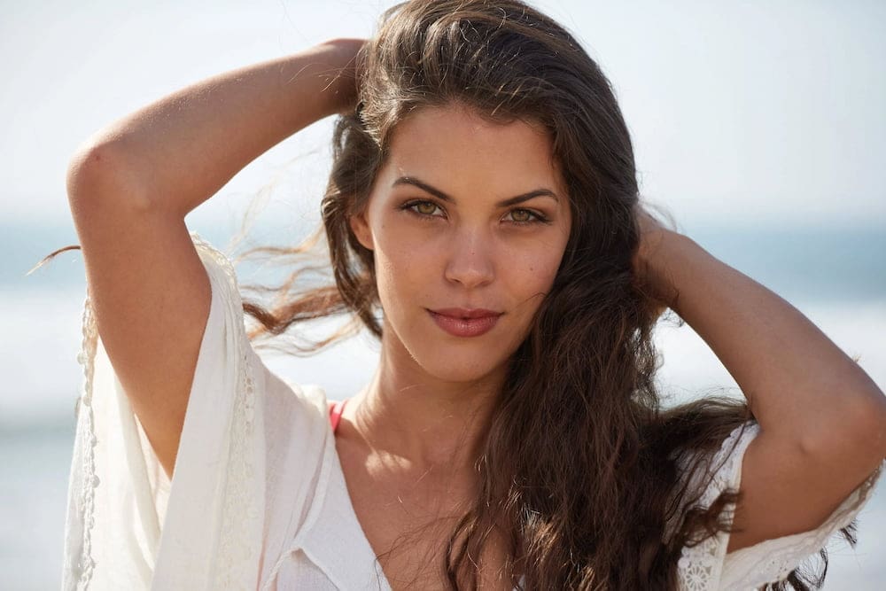 Displaying healthy hair after PRP at Refresh MedSpa in Cape Coral FL, a woman with long brown hair stands outdoors, hands in hair.