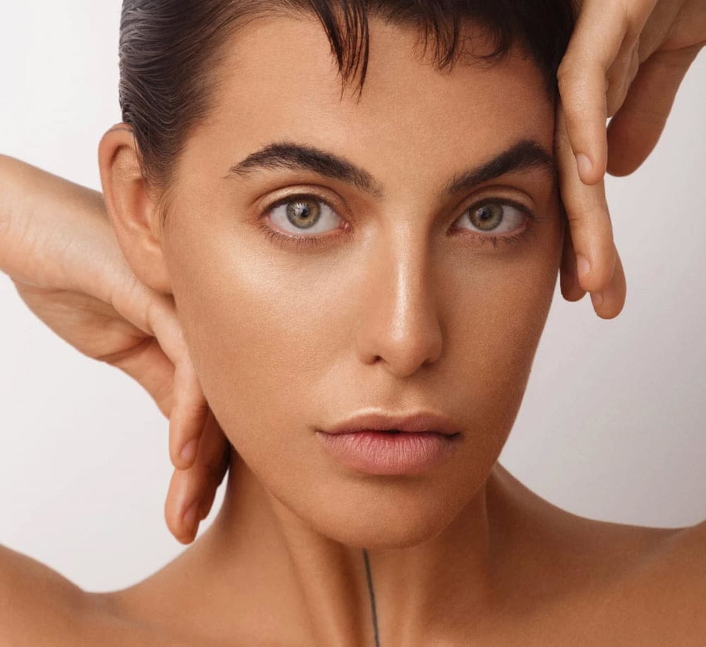 A person with light eyes and smooth skin poses at Refresh MedSpa, hands framing their face to show wrinkle relaxer results.